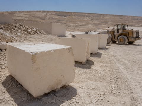 Row of freshly extracted cream marble blocks at the Minya quarry with a wheel loader