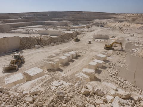 Raya Stone Minya quarry: terraced benches with rows of extracted marble blocks, a wheel loader and an excavator